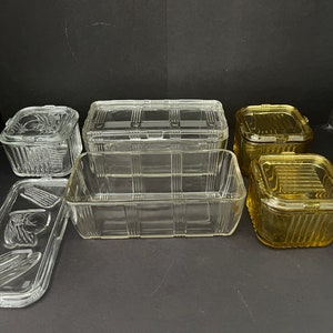 May include: Set of six vintage glass storage containers with lids. The containers are clear glass with a grid pattern and the lids are clear glass with a raised design. Two of the containers are amber glass with a grid pattern.