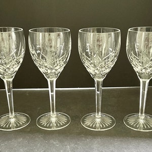 May include: Set of four clear glass wine glasses with a cut crystal design. The glasses have a tall, slender stem and a round bowl.