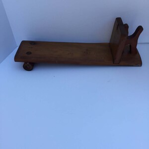 May include: A wooden bookend with a simple design. The bookend is made of two pieces of wood, one of which is shaped like a rectangle and the other like a triangle. The two pieces are joined together at a right angle.