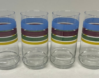 May include: Set of four clear glass drinking glasses with colorful stripes. The stripes are blue, maroon, green, and yellow.