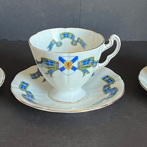 May include: Three teacups and saucers with floral designs. The teacups are white with gold trim and feature different floral patterns. The saucers are white with a floral pattern.