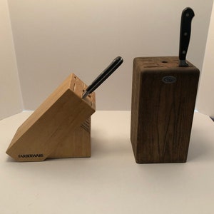 May include: Two wooden knife blocks, one brown and one light wood. The light wood block has the word "Farberware" printed on the front. The brown block has a small metal tag with the word "Cuisinart" printed on it.