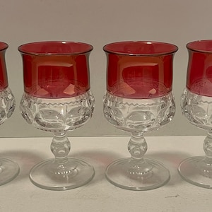 May include: Set of four clear glass wine glasses with a red, ruby-colored rim. The glasses have a textured, diamond-shaped pattern.
