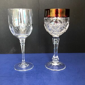 May include: Two clear glass wine glasses. One glass has a cut crystal design and the other has a plain design. Both glasses have a stem and a round base.