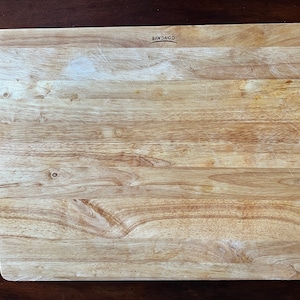 May include: A rectangular wooden cutting board with a light brown color and a slightly concave surface. The board has a "CONCAVE" logo printed on the top right corner.