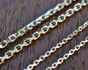 May include: Three silver chains of different thicknesses and link styles, laid out on a wooden surface.
