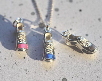 May include: Three silver shoe charms, one with a pink accent, one with a blue accent, and one with a silver accent. The charms are hanging from a silver chain.