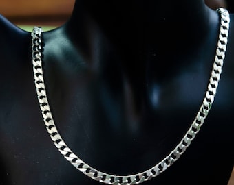 Op de afbeelding: Een zilveren curb chain ketting op een zwart manekin.