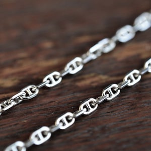 Puede incluir: Un collar de cadena marinera de plata, con un primer plano de los eslabones.