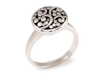 May include: A silver ring with a round, textured top featuring a swirling, floral design.