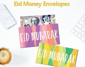 May include: Two colorful envelopes with the text "Eid Mubarak" printed on them. The envelopes are decorated with geometric patterns in shades of pink, purple, orange, yellow, and green. A Canadian ten dollar bill is visible inside one of the envelopes.
