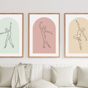 May include: Three framed prints with a minimalist line drawing of a ballerina in a different pose on each print. The backgrounds are a light green, a light pink, and a light yellow.