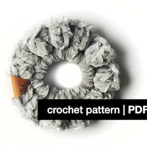 Puede incluir: Un scrunchie para el pelo de crochet gris con una etiqueta de cuero marrón que dice "The Knotty Knitter". patrón de crochet | PDF
