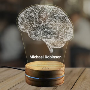 May include: A 3D printed brain-shaped night light with a wooden base. The base has a power switch and the name "Michael Robinson" is printed on the front.