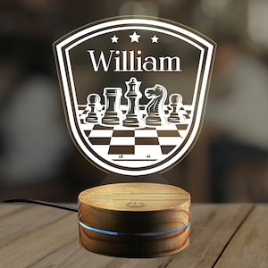 May include: A white personalized night light with a chessboard design and the name "William" in a shield shape. The light sits on a wooden base.