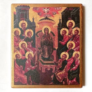 May include: A rectangular wooden icon featuring a central figure seated on a throne, surrounded by a group of figures with golden halos. The scene is set against architectural structures with a red and gold color palette and a dove at the top.