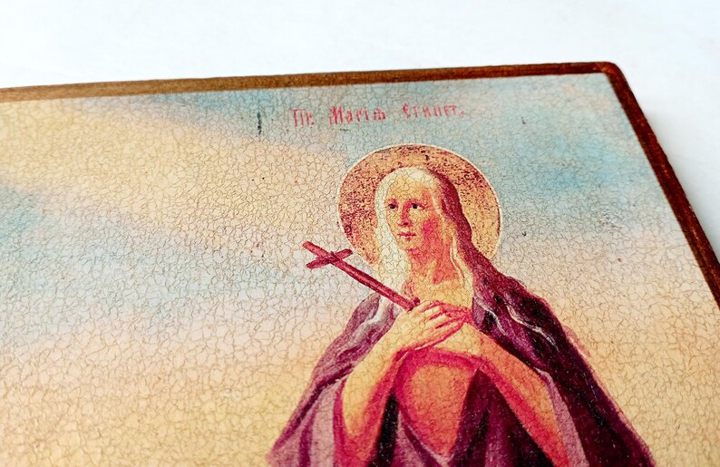 K&ouml;nnte beinhalten: Vintage religi&ouml;se Illustration einer Frau mit Heiligenschein und Kreuz. Das Bild hat ein gealtertes Aussehen mit sichtbaren Rissen. Der Text "The Maria Gruner" ist oben sichtbar. Vintage-&Auml;sthetik.