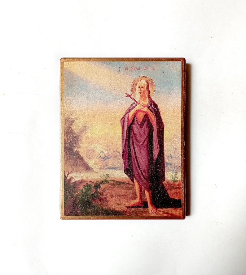 K&ouml;nnte beinhalten: Vintage religi&ouml;se Ikone mit einer Figur in einem lila Gewand, die ein Kreuz h&auml;lt. Das Bild hat einen goldenen Rahmen und einen Landschaftshintergrund mit Sonnenuntergang. Der Text "The Maria Gisher" steht oben.