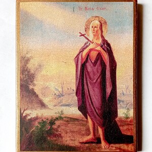 K&ouml;nnte beinhalten: Vintage religi&ouml;se Ikone mit einer Figur mit Heiligenschein, die ein Kreuz h&auml;lt. Die Figur ist in ein lila Gewand geh&uuml;llt, vor einer Landschaft mit goldenem Rahmen. Der Text "St. Maria E." ist oben sichtbar.