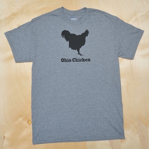 May include: A heather gray t-shirt with a black silhouette of a chicken shaped like the state of Ohio. The text "Ohio Chicken" is printed below the chicken.