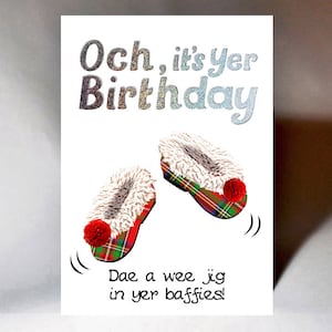 May include: A white card with a glittery silver text that says "Och, it's Yer Birthday". The card has a drawing of two red and green plaid slippers with white fur trim and red pom-poms. The text below the slippers says "Dae a wee jig in yer baffies!"