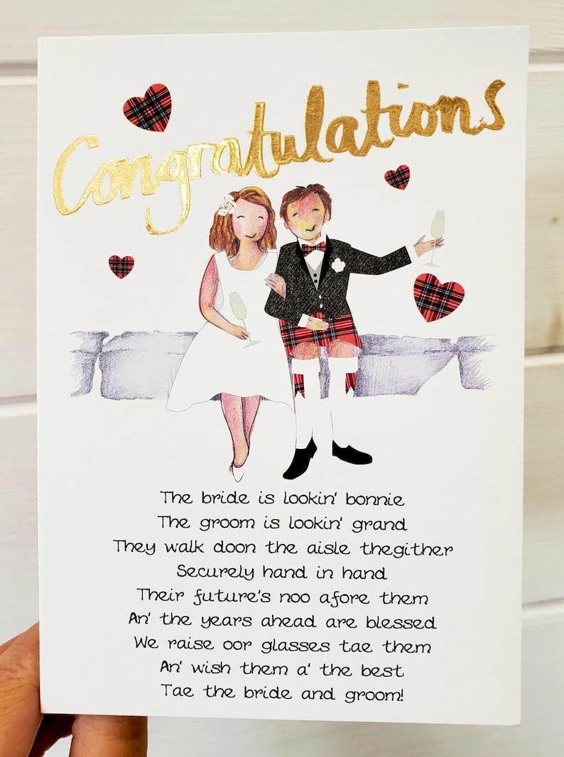 Puede incluir: Una tarjeta de boda con una ilustraci&oacute;n de dibujos animados de una novia y un novio con atuendos tradicionales escoceses. La tarjeta tiene una inscripci&oacute;n en pan de oro que dice "Felicidades". El texto en la tarjeta dice: "The bride is lookin' bonnie, The groom is lookin' grand, They walk doon the aisle thegither, Securely hand in hand, Their future's noo afore them, An' the years ahead are blessed, We raise oor glasses tae them, An' wish them a' the best, Tae the bride and groom!"