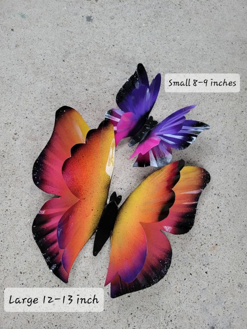 May include: Three metal butterflies in a gradient of pink, orange, and purple. The butterflies are in different sizes, with the largest measuring 12-13 inches and the smallest measuring 8-9 inches.  "Small 8-9 inches" and "Large 12-13 inch" are written in white text on a black background.