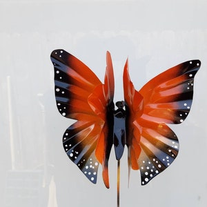 May include: Orange and black metal butterfly garden stake with white dots. The butterfly is made of metal and has a realistic design.
