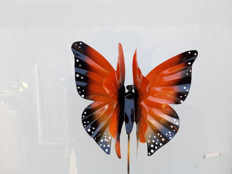 May include: Orange and black metal butterfly garden stake with white dots. The butterfly is made of metal and has a realistic design.