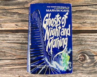 May include: A blue paperback book with a white title, "Ghosts of Night and Morning", and a black and white illustration of a staircase. The book is the sequel to "A Cold Blue Light" by Marvin Kaye.