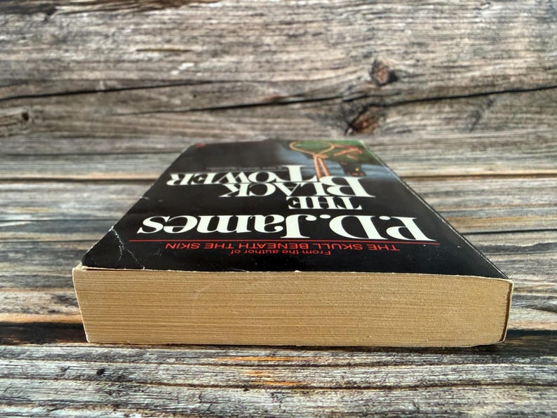 May include: A hardcover book titled "The Black Tower" by P.D. James. The book has a black cover with white lettering and a picture of a person. The book's pages are aged, and the spine is slightly worn.