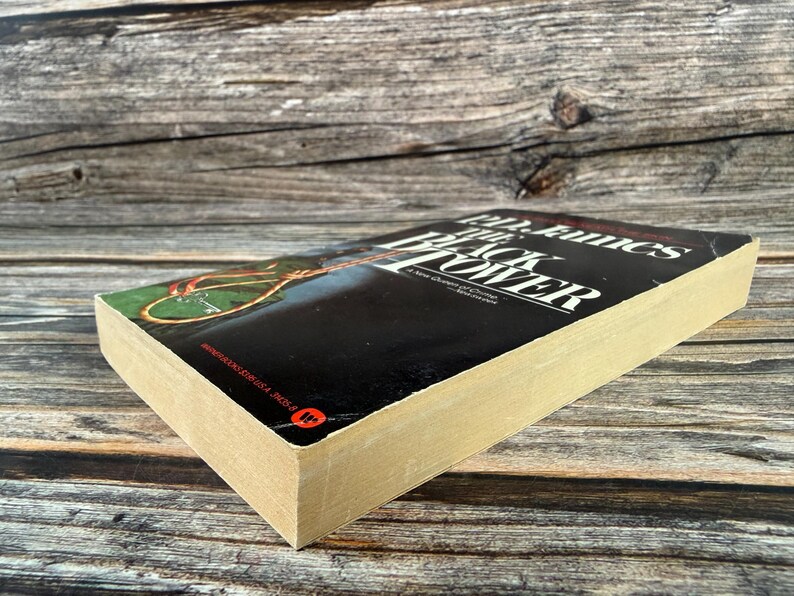 May include: A hardcover book titled "The Black Tower" by John Fowles. The book has a black cover with white text and a colorful illustration. The book's pages are aged, and the spine is visible.