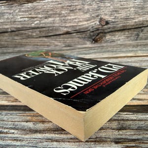May include: A hardcover book titled "The Black Tower" by Ed James. The book has a black cover with white and red text. The book is lying on a wooden surface.