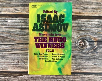 May include: A book cover with a yellow, green, and orange watercolor background. The title is "The Hugo Winners Vol. II" and the book is edited by Isaac Asimov. The cover features the names of the authors included in the book: Philip José Farmer, Harlan Ellison, Fritz Leiber, Robert Silverberg, Samuel R. Delany, Poul Anderson, and Anne McCaffrey.