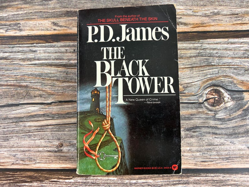 May include: A vintage paperback book titled "The Black Tower" by P.D. James. The cover is black with white lettering and features a lighthouse illustration with a noose and key. The book is a Warner Books edition.