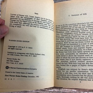 May include: Open book with text on aged paper. The text includes the title "Sentence of Life" and copyright information for a 1975 Warner Books edition by P. D. James. The book is open to a page with text.