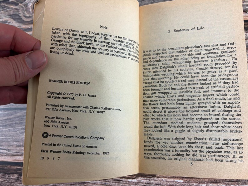 May include: Open book with text on aged paper. The text includes the title "Sentence of Life" and copyright information for a 1975 Warner Books edition by P. D. James. The book is open to a page with text.