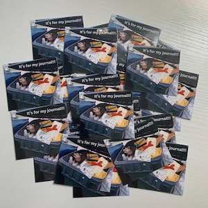 May include: A collection of square stickers featuring a graphic of an opossum sitting inside a grey plastic bin filled with various items, including a MetroCard and a red ribbon. The text "It's for my journal!!!" is printed at the top of each sticker.