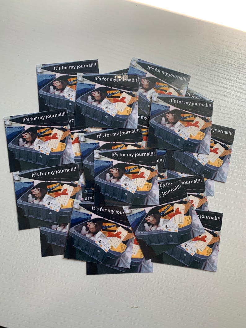 May include: A collection of square stickers featuring a graphic of an opossum sitting inside a grey plastic bin filled with various items, including a MetroCard and a red ribbon. The text "It's for my journal!!!" is printed at the top of each sticker.