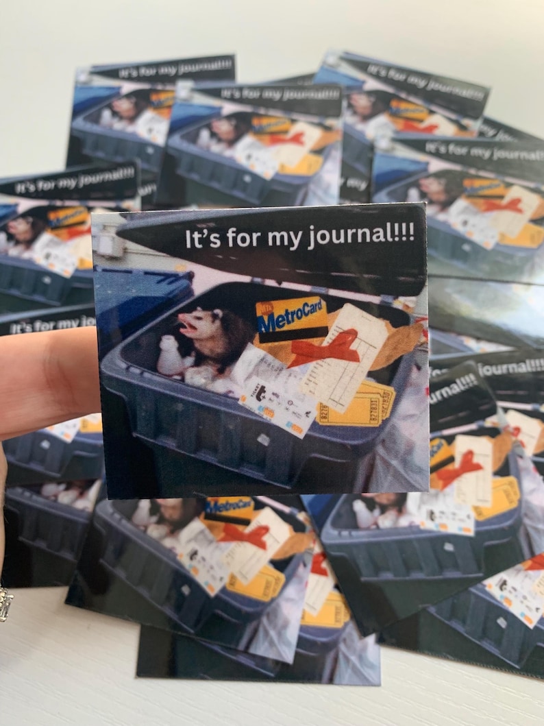 May include: A square sticker featuring a photograph of an opossum inside a dark gray trash bin filled with various items including a MetroCard, a red ribbon, and paper scraps. The text "It's for my journal!!!" is printed in white at the top.