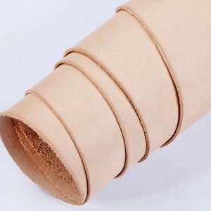 May include: A roll of natural leather in a light beige color. The leather is rolled up tightly and the edges are visible.