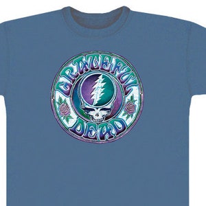 Puede incluir: Una camiseta azul con un logotipo colorido de Grateful Dead que presenta una calavera y un rayo. El logotipo está rodeado por un círculo con las palabras "Grateful Dead" escritas alrededor.