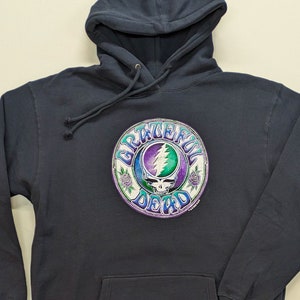 May include: A navy blue hooded sweatshirt with a large, colorful Grateful Dead logo printed on the front. The logo features a skull with a lightning bolt and the words "Grateful Dead" in a circular design.