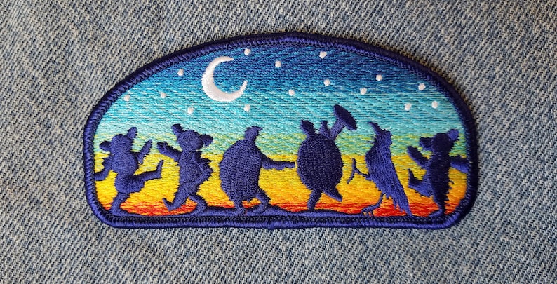 May include: Embroidered patch featuring a colorful night sky with a crescent moon and stars. Seven silhouettes of dancing figures are depicted against the sky, including a bear, a turtle, and a bird.