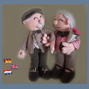 May include: Two crocheted figures of an elderly couple, the man wearing a brown hat and jacket, the woman wearing a pink jacket and holding a bouquet of pink flowers.