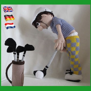May include: A crocheted golfer doll wearing a white hat, blue shirt, and yellow and blue checkered pants. The doll is holding a golf club and is standing next to a brown golf bag with three golf clubs.