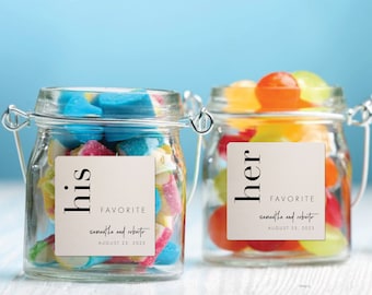 Op de afbeelding: Twee glazen potten gevuld met kleurrijke snoepjes, elk met een wit vierkant etiket. Het etiket op de linker pot zegt "his" en het etiket op de rechter pot zegt "her". Beide etiketten bevatten de tekst "FAVORITE samantha and roberto AUGUST 23, 2023".