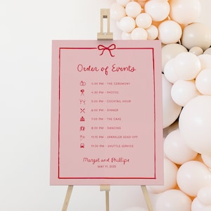 Letrero con orden de eventos para el día de la boda con cinta y lazo, cronograma y calendario extravagantes en rojo y rosa, letrero de bienvenida con íconos, SN800_OOE