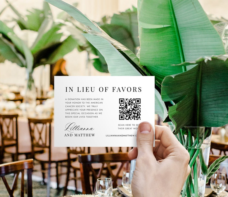 May include: A white card with black text that reads "In Lieu of Favors" and a QR code. The text explains that a donation has been made to the American Cancer Society in honor of the couple's wedding. The card is signed "Lillianna and Matthew".