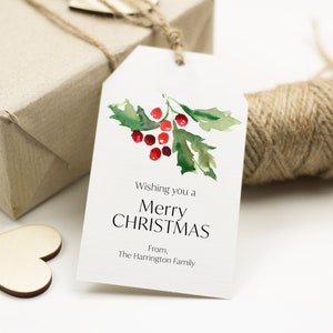 May include: White Christmas gift tag with watercolor holly and berries. The tag reads "Wishing you a Merry Christmas" and "From, The Harrington Family". A wrapped gift and twine are in the background.
